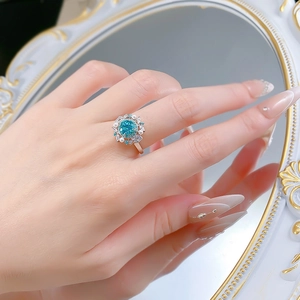 Macro view of floral s925 silver ring with teal gemstone, pearls, and diamonds on finger