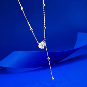 Detail of elegant Y-shaped gold lariat necklace featuring a pear-cut crystal teardrop pendant