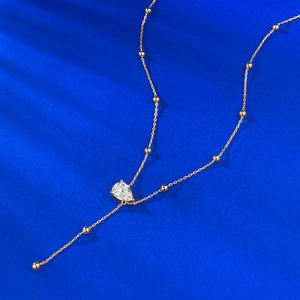 Elegant gold bead chain necklace with pear-cut teardrop pendant on deep blue texture