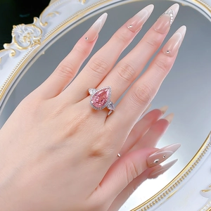 Luxurious 925 silver halo ring with large pear-cut pink stone on a model hand