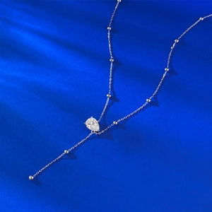 Macro view of S925 silver Y-shaped necklace with pear-cut stone on blue background