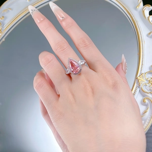 Detailed view of pear cut pink stone ring with halo setting and three-stone design