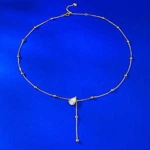 Macro detail of gold Y-shaped necklace featuring a pear-cut stone and beaded tassel drop