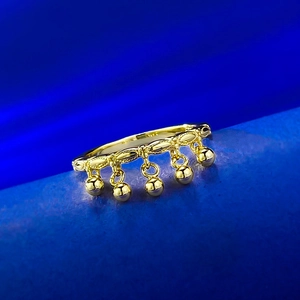 Detail of a gold tassel ring featuring hanging beads on a textured blue fabric backdrop