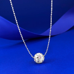 Detail of S925 silver brushed ball pendant with pink zircon on blue silk background