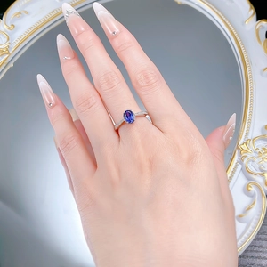 Model wearing an oval blue sapphire ring set in silver metal with small side diamonds