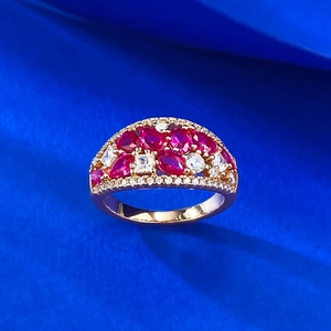 Macro detail of rose gold ring with red rubies and white zircon stones on blue texture
