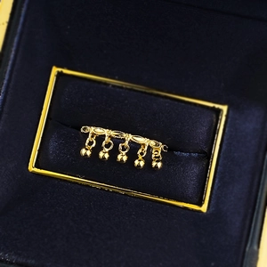 Detailed close-up of golden ring with five bead charms in a luxury navy blue velvet box
