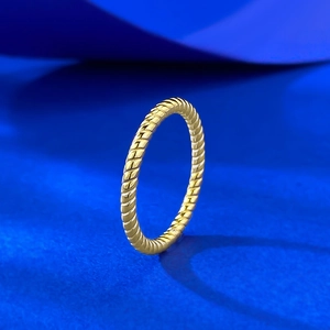 Polished golden twisted rope ring in 925 silver on a textured blue background