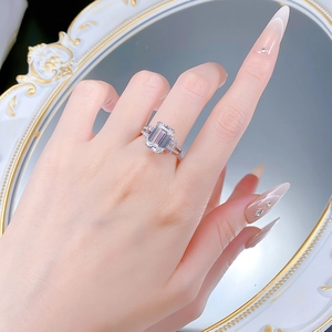 Close-up of emerald-cut rectangular white stone ring worn on hand with vintage mirror background