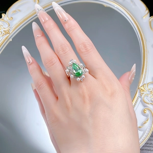 Detail of a teardrop green gemstone ring with white pearls and zircon on a woman's hand