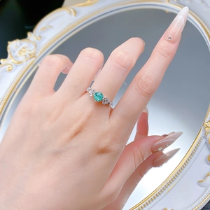 Detail shot of a 6.0mm Paraiba blue round stone ring with side diamonds on finger