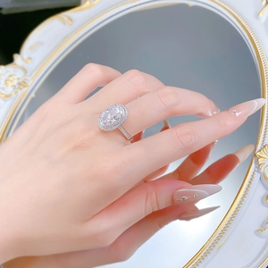 Detailansicht eines funkelnden ovalen Rings am Finger mit eleganten Nägeln