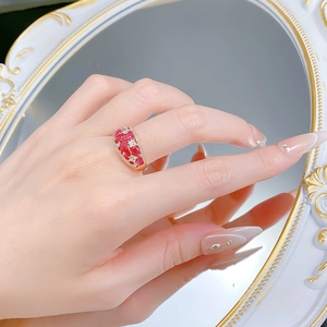 Close-up of luxury gold ring with pear-cut rubies and white zircon pavé on hand