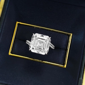 Close-up of Asscher cut white zircon ring with pavé stones in a blue velvet box