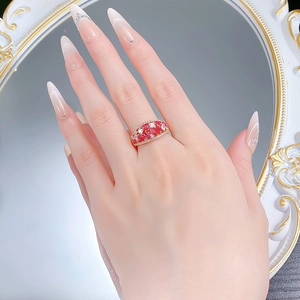 Close-up of a gold ring featuring marquise-cut red stones and white zircon on a hand