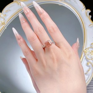 Vue macro d'une bague saphir rose rectangulaire avec diamants pavés sur une main femme