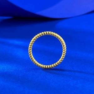 Macro shot of gold twisted rope ring with a smooth metallic finish on blue background