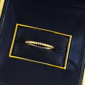 Macro shot of gold ribbed ring texture displayed on deep blue velvet jewelry box
