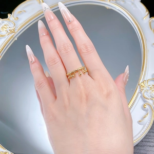 Detailed view of a gold tassel ring with dangling beads on a vintage mirror surface