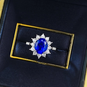 Macro shot of a floral S925 silver ring featuring an oval blue gem in a velvet box