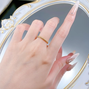 Detail of twisted rope gold ring band on finger against a vintage mirror backdrop