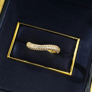Detailed view of a wave-shaped gold-plated ring with shimmering paved diamonds and stones