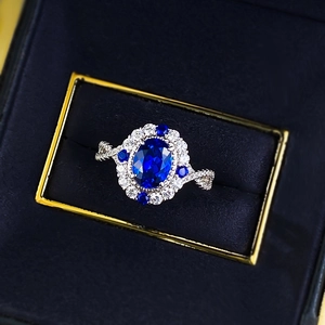 Macro detail of oval blue gemstone ring with cluster setting and twisted pave band