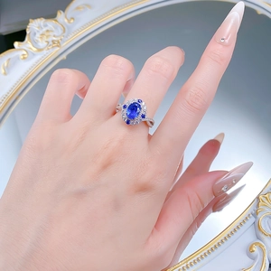 Detailed view of an oval blue sapphire ring with halo diamonds on a silver twisted band