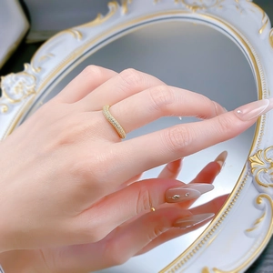 Detail of a wavy gold ring with micro-pave diamonds on a hand with mirror background