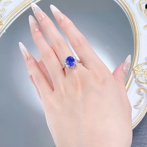 Detail of oval blue sapphire ring with starburst halo and diamonds on silver band