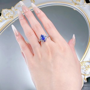 Detail view of oval blue gemstone ring with pave twisted band on model hand