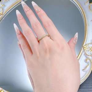 Detail of a wavy gold ring with micro-pave diamonds on a hand model by a mirror