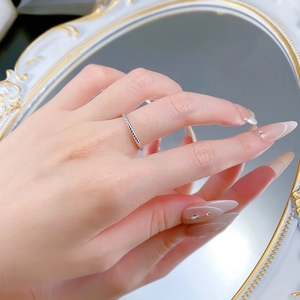 Macro detail of minimalist silver twisted rope ring worn on finger with vintage mirror background