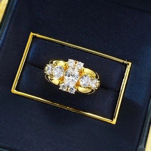 Macro view of oval white gemstone cluster ring on navy blue velvet jewelry box