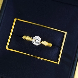 Detaillierte Makroaufnahme eines goldfarbenen Bambus-Rings mit rundem Solitär-Edelstein