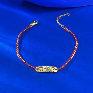 Macro detail of red woven cord bracelet with gold zodiac charms and lobster clasp
