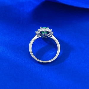 Macro shot of S925 silver ring featuring a green halo-set emerald-cut gemstone