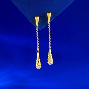 Detailed view of long gold drop earrings with tassel chains and pavé set crystals