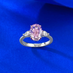 Top view of pink oval sapphire ring with pear-shaped side stones on blue background