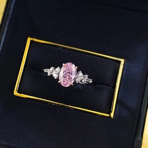 Macro shot of an oval pink gemstone ring with cluster diamonds in a jewelry box