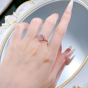 Detail of S925 silver ring featuring pink oval gemstone and side stones on a finger