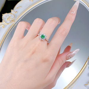 Close-up of S925 silver ring featuring emerald-cut green gemstone with flower halo detail