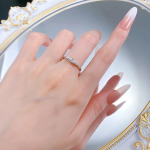 Detailed view of a slender silver ring with three baguette-cut stones on a model's finger
