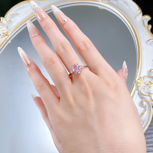 Close-up of S925 silver ring with pink oval gemstone and side stones worn on finger