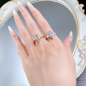 Detailed view of marquise cut rings in gold and silver finish on hand with crystal accents