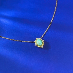 Detail of vintage gold necklace featuring green opal pendant with diamond accents