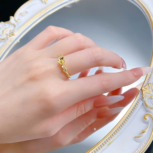 Detail of gold floral ring with twisted band and clear stones worn on a model's hand