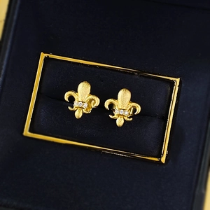 Macro detail of gold brushed S925 silver fleur-de-lis earrings with small inlaid stones