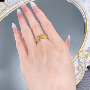 Détail d'une bague dorée ondulée avec zircons portées sur une main aux ongles soignés